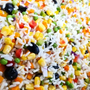 Salade de riz avec du maïs, des carottes, des olives noires, des tomates et des petits pois