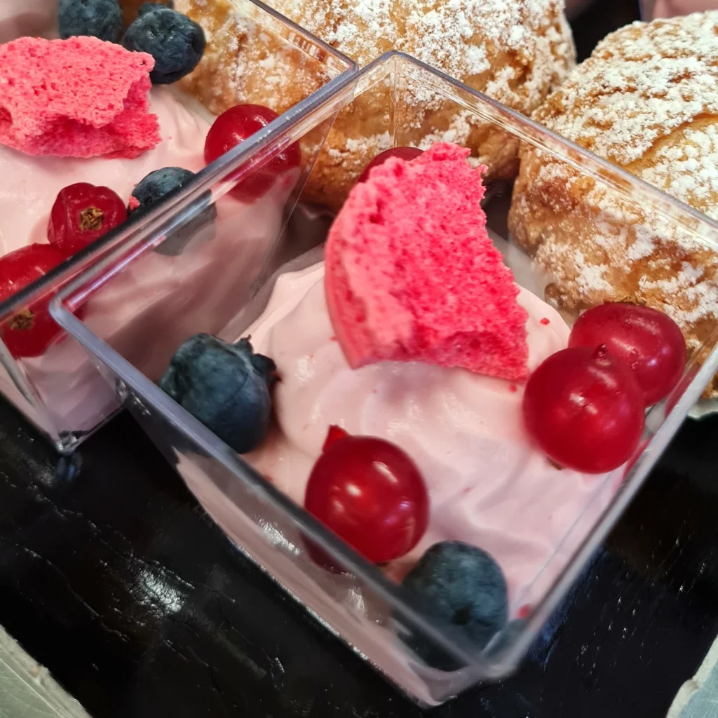 Verrine avec de la mousse aux fruits rouges et des fruits rouges en décoration