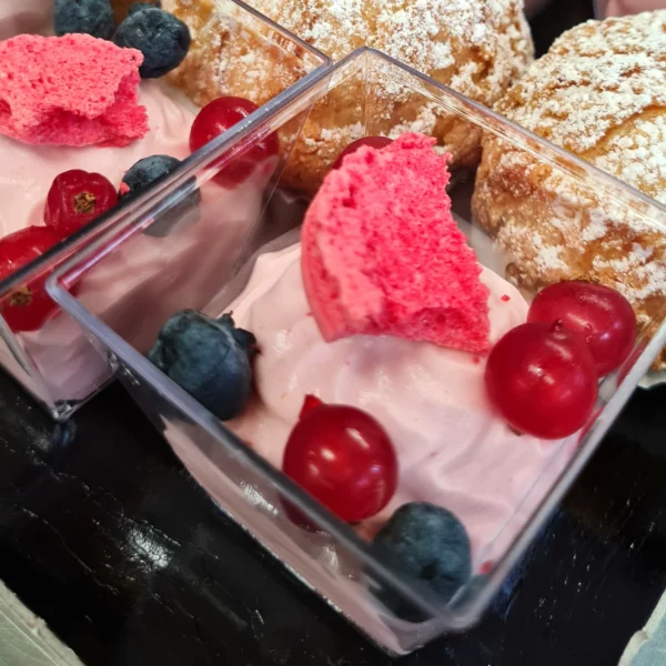 Verrine avec de la mousse aux fruits rouges et des fruits rouges en décoration